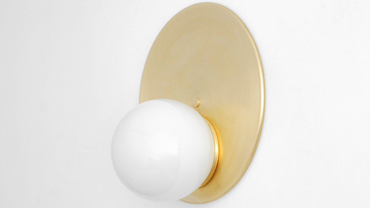 Mid-century modern wall sconce with raw brass circular backplate and white globe shade. - SCONCE MODEL NO. 6703