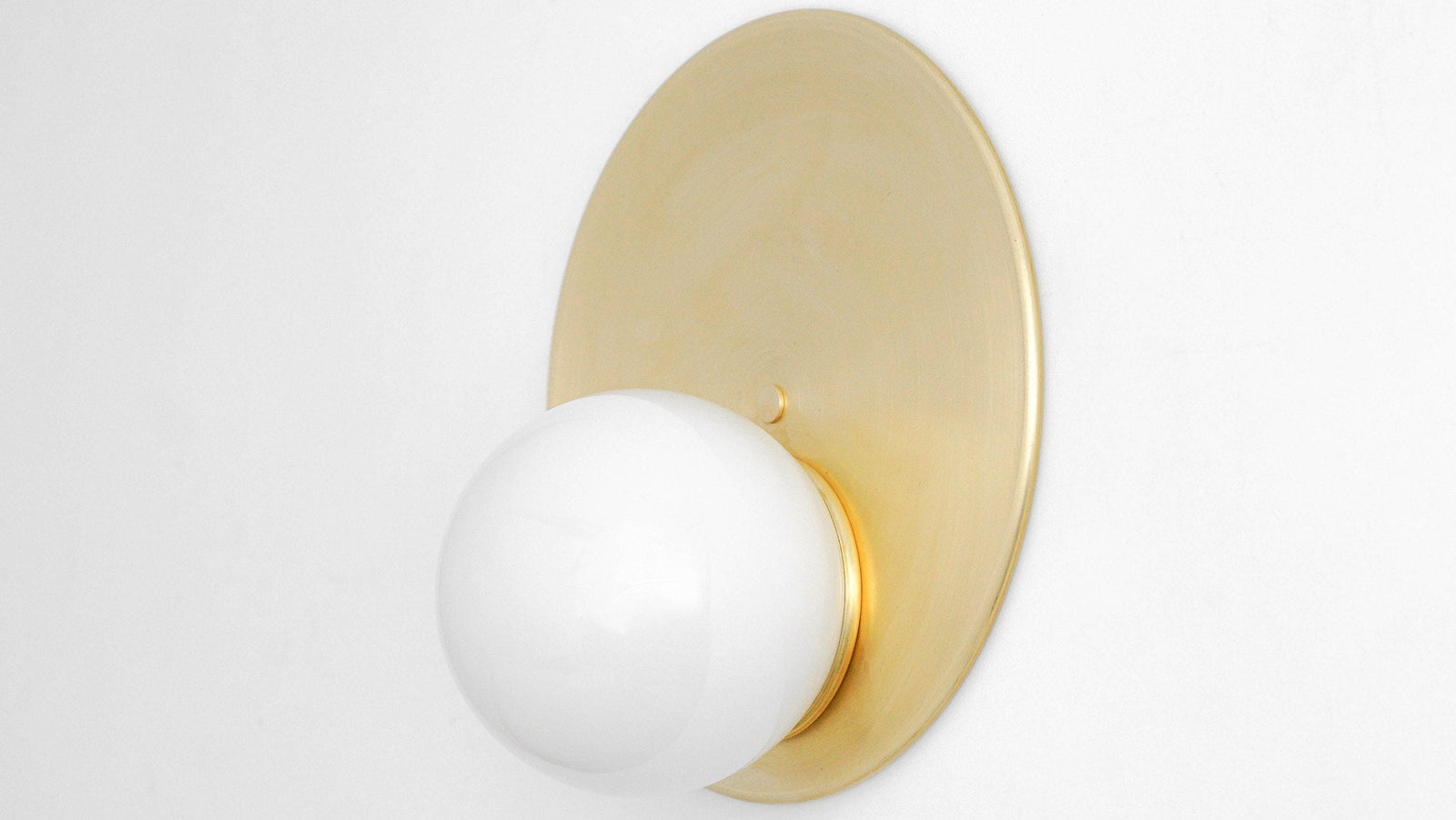 Mid-century modern wall sconce with raw brass circular backplate and white globe shade. - SCONCE MODEL NO. 6703