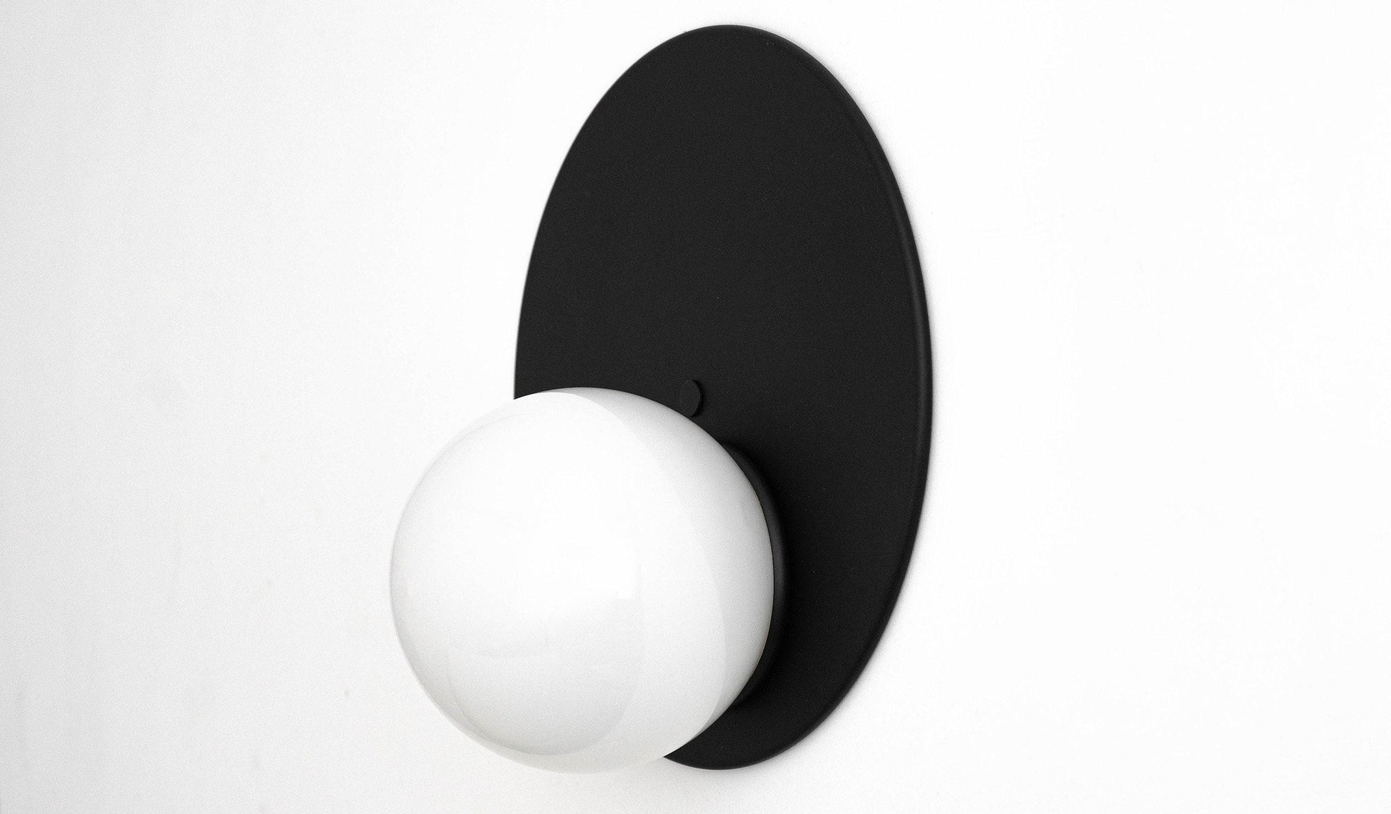 Mid-century modern black oval backplate wall sconce with white globe shade. - SCONCE MODEL NO. 6703