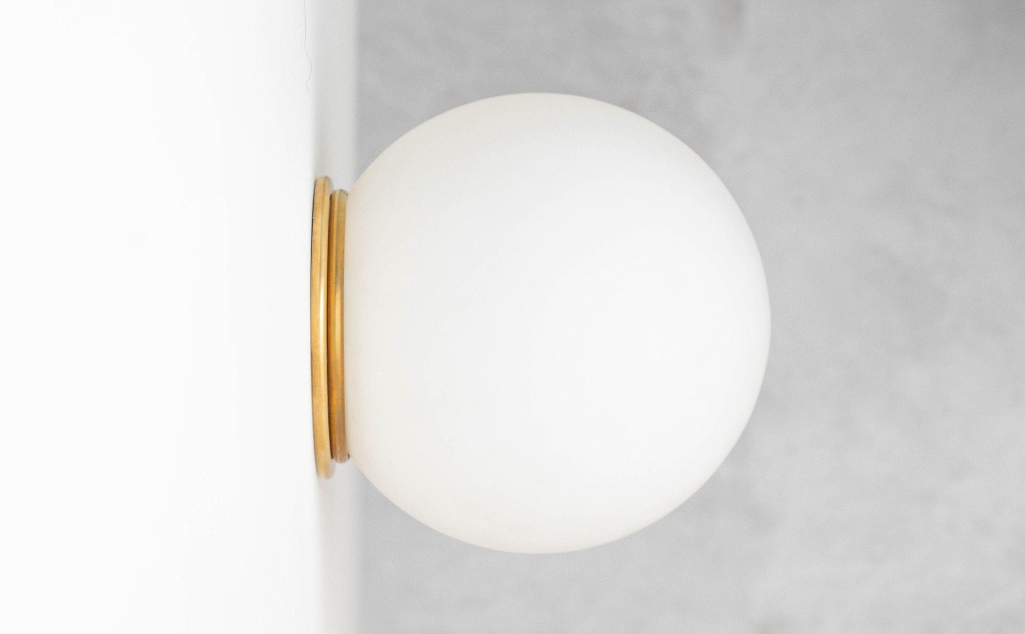 Mid-century modern wall sconce with frosted glass globe and raw brass flush mount. - SCONCE MODEL NO. 4037