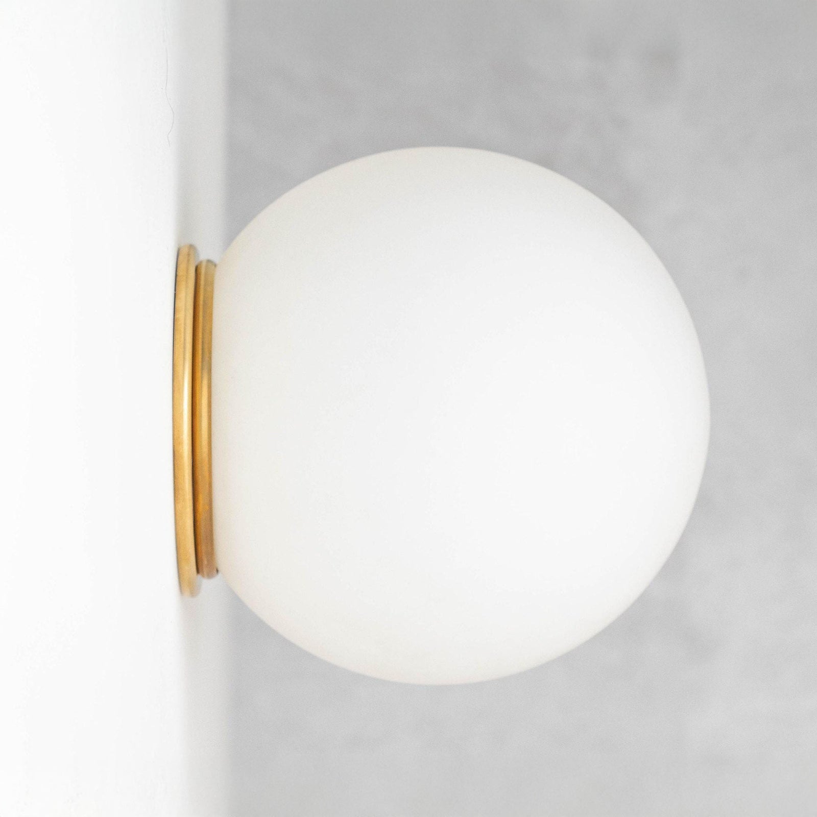 Mid-century modern wall sconce with a frosted white globe and raw brass flush mount. - SCONCE MODEL NO. 4037
