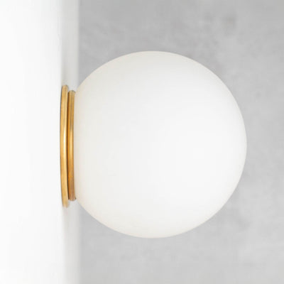 Mid-century modern wall sconce with a frosted white globe and raw brass flush mount. - SCONCE MODEL NO. 4037