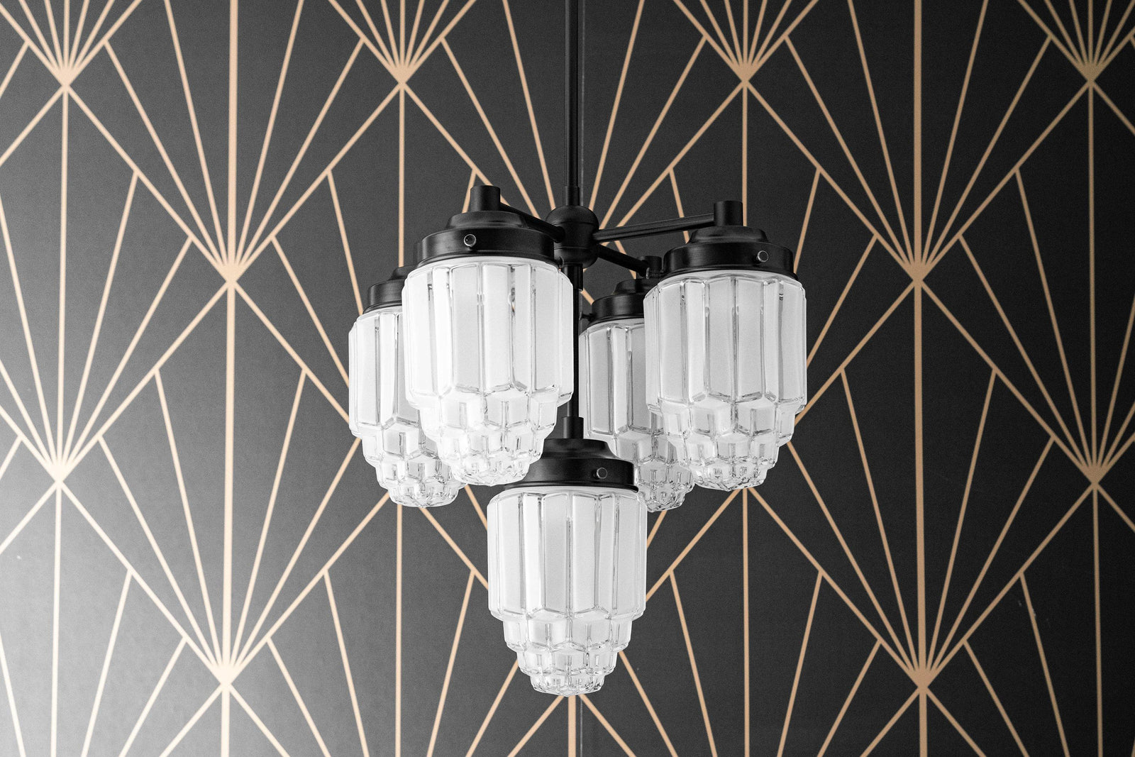 Black metal Art Deco chandelier with five frosted globe glass shades against geometric gold and black wallpaper. - CHANDELIER MODEL NO. 0777