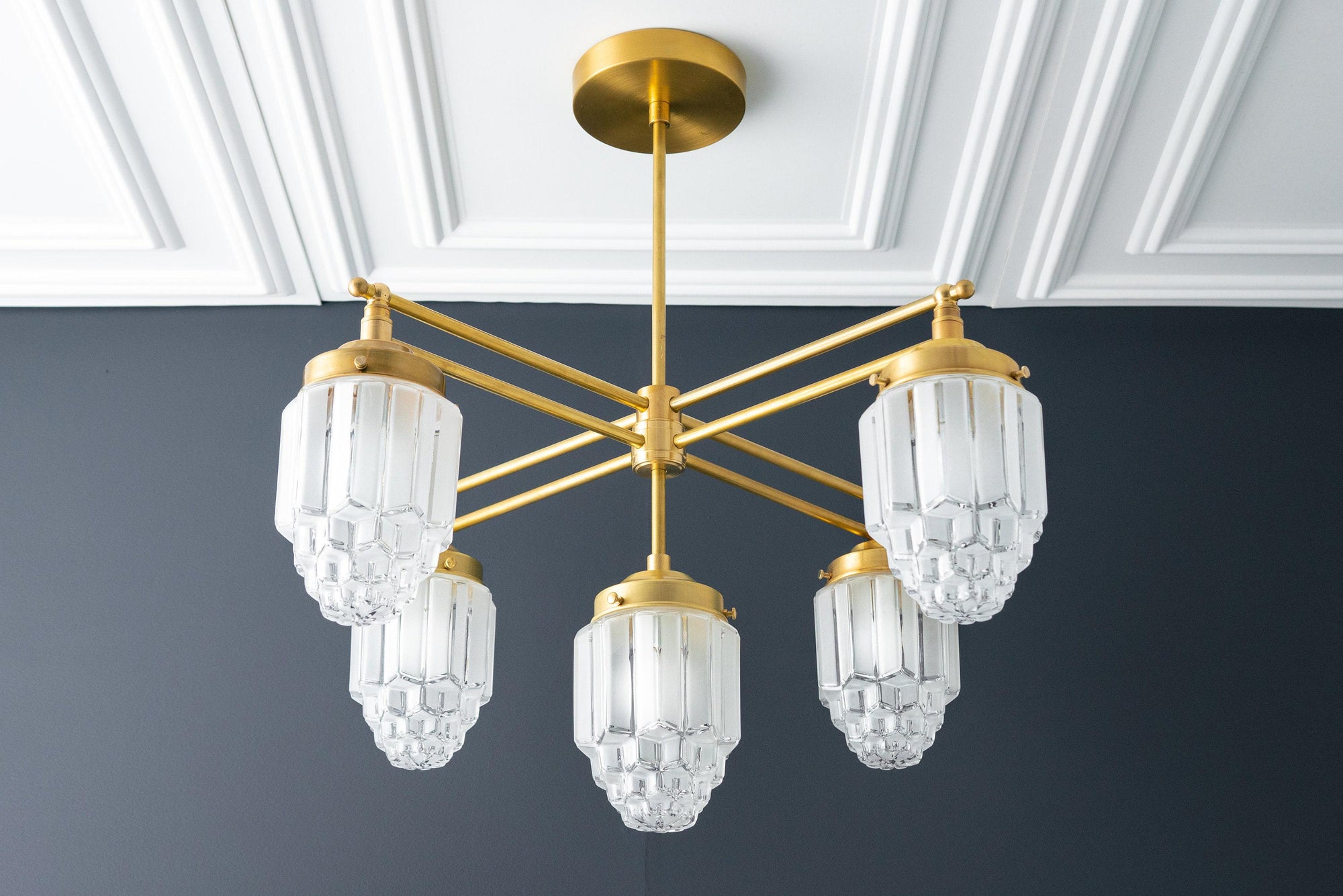 Art Deco chandelier with six raw brass arms and clear globe glass shades against white ceiling panels. - CHANDELIER MODEL NO. 5830