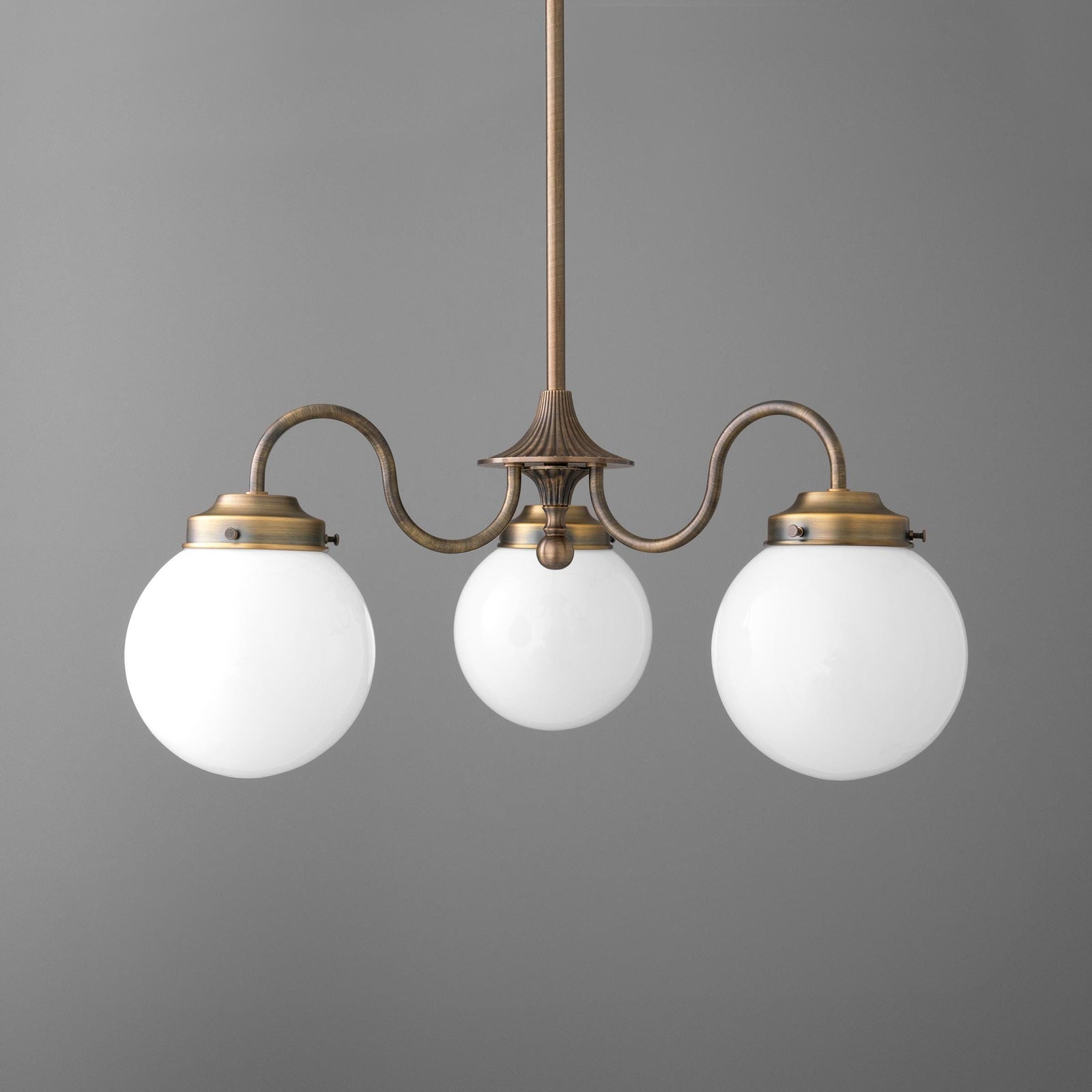 Antique brass chandelier with three white glass globe shades and curved arms against gray background. - CHANDELIER MODEL NO. 5877