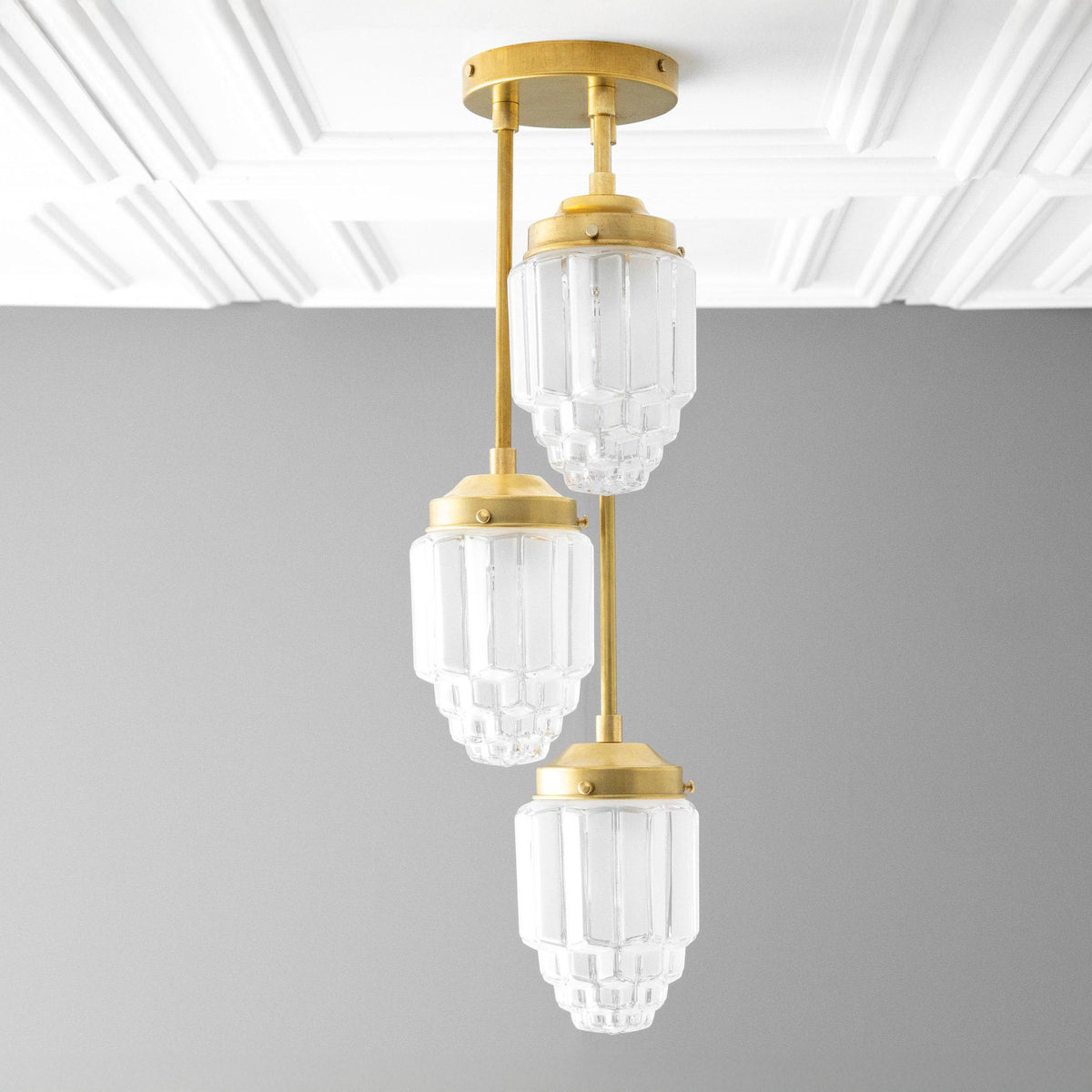Three-light cascading chandelier in Raw or Sealed Brass with ribbed tiered shades hung at staggered heights. - CHANDELIER MODEL NO. 7948