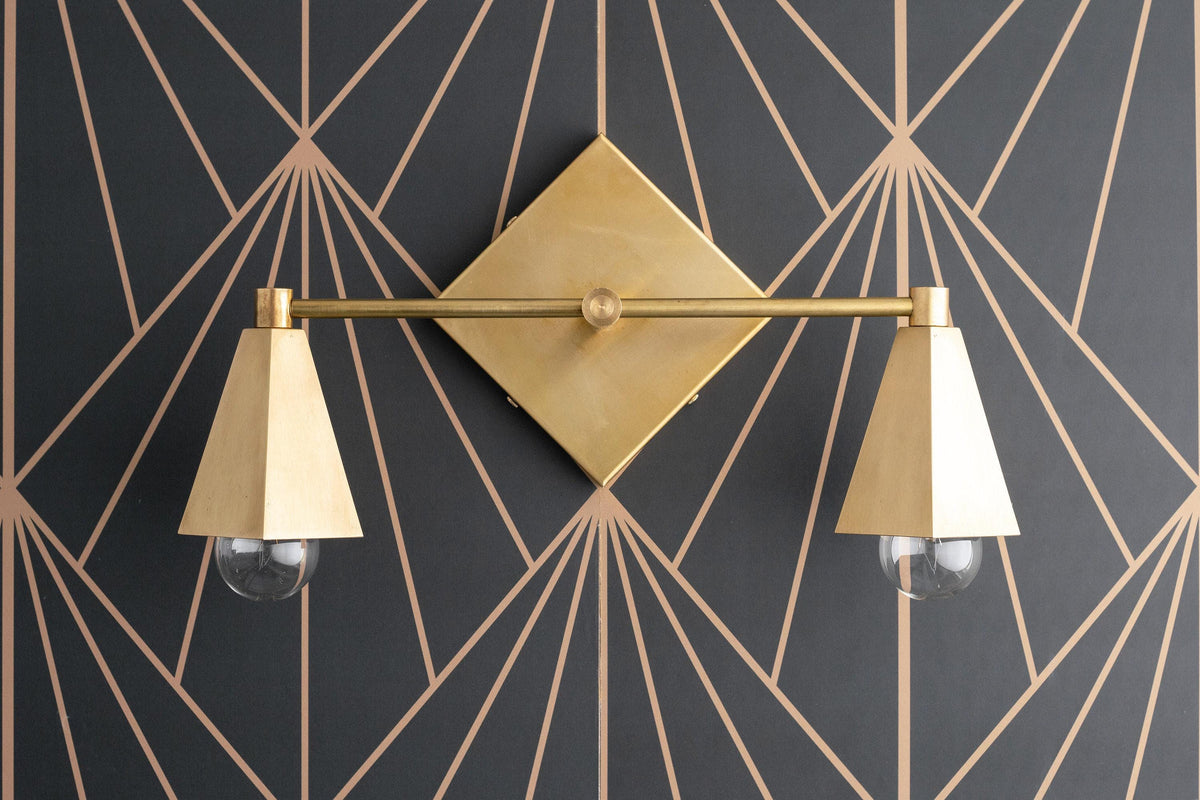 Art Deco two-bulb vanity light in raw brass with cone-shaped white shades and decorative backplate. - VANITY LIGHT MODEL NO. 4237