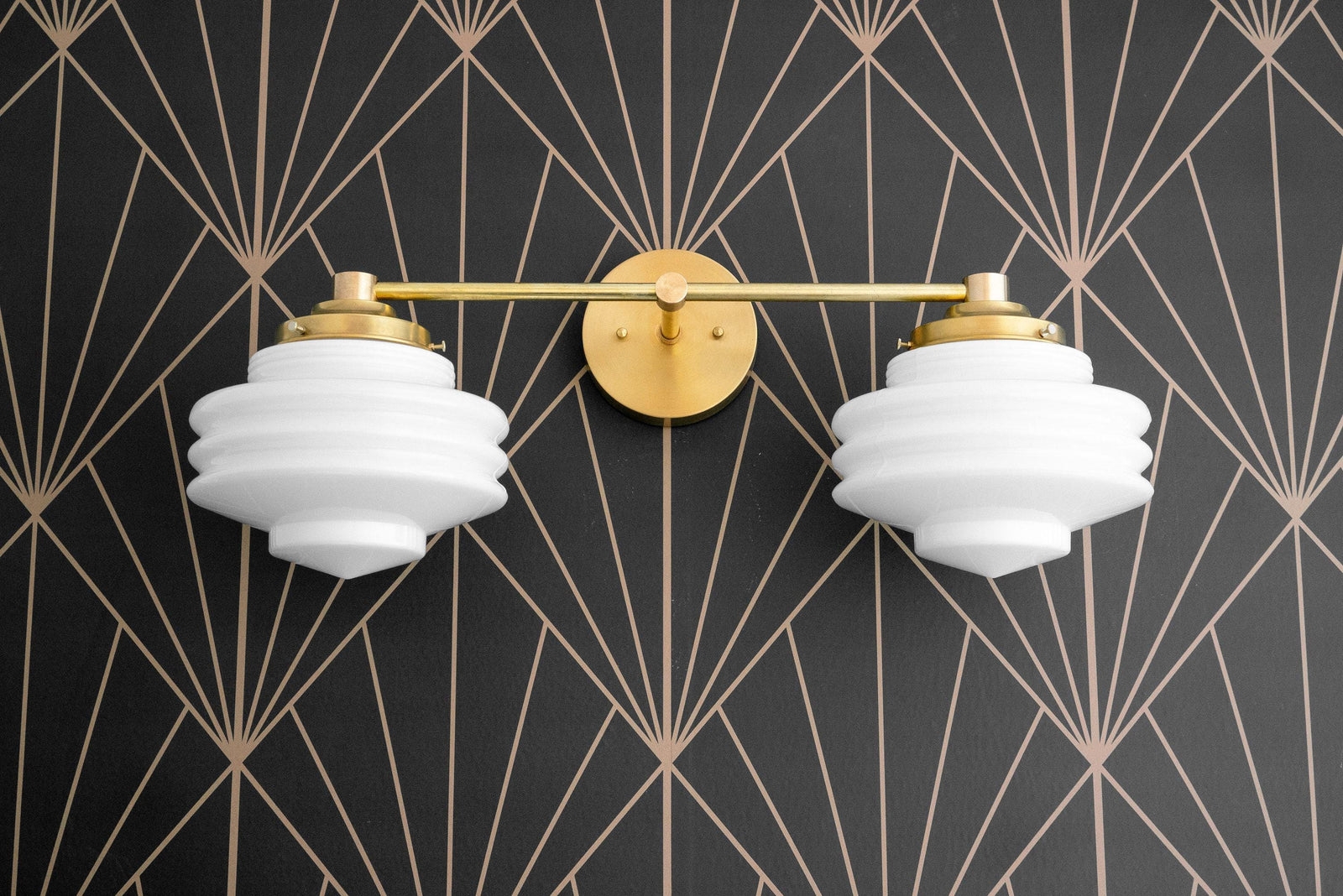 Two-bulb vanity light in polished brass with white globe shades against black and gold geometric wallpaper. - VANITY LIGHT MODEL NO. 9479