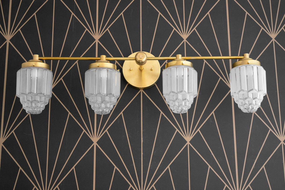 Art Deco 4-bulb vanity light with polished brass finish and geometric clear glass globes against black and gold patterned. - VANITY LIGHT MODEL NO. 1082