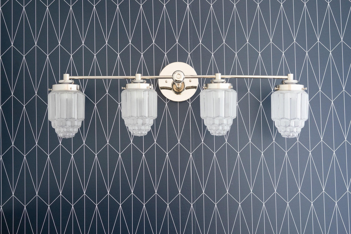 Polished nickel 4-bulb vanity light with white art deco globe shades on geometric patterned wall. - VANITY LIGHT MODEL NO. 1082