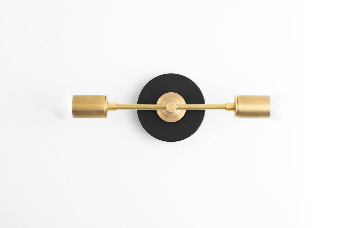 Art Deco vanity light with black circular mount and raw brass cylindrical shades and rod. - VANITY LIGHT MODEL NO. 8057