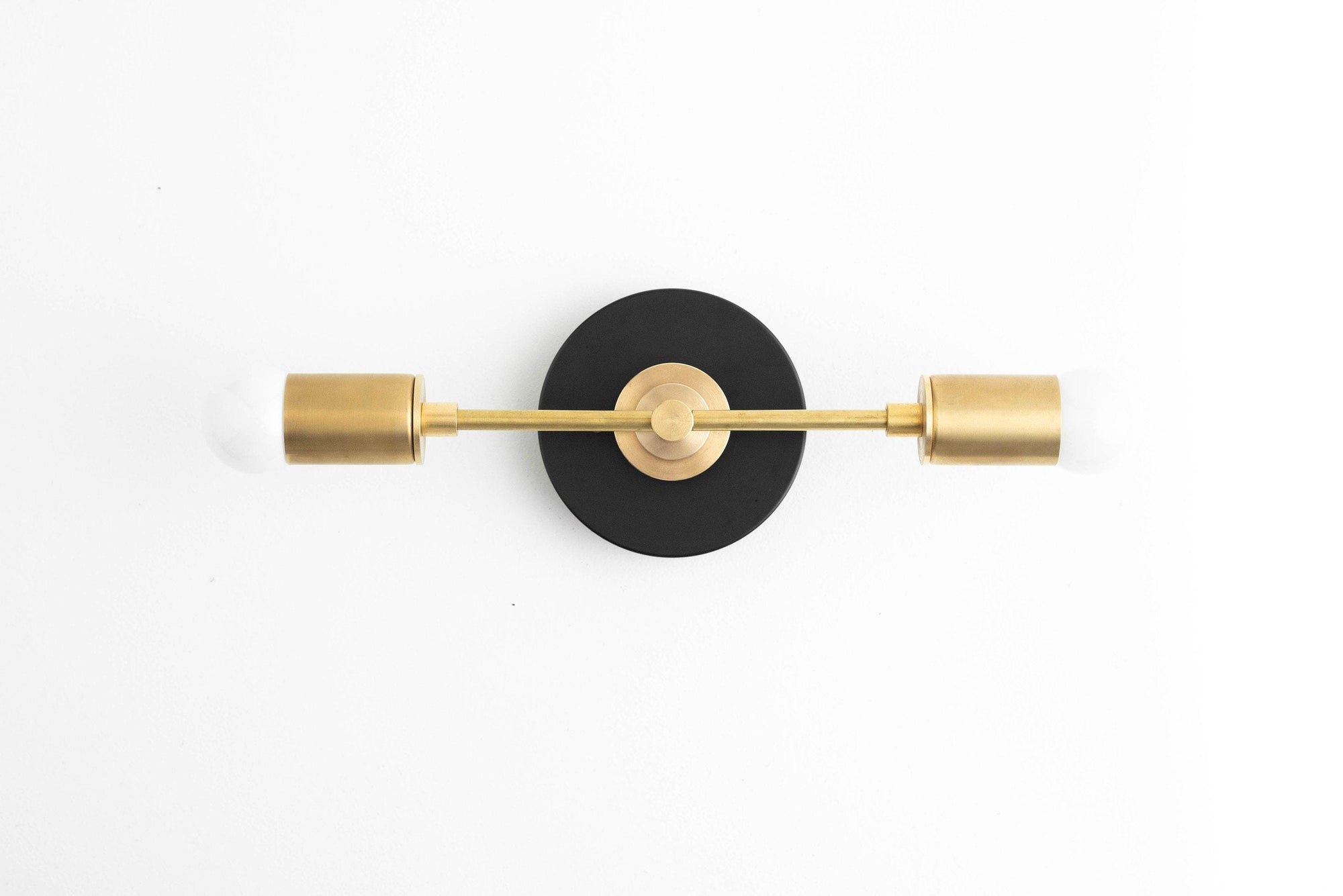 Art Deco vanity light with black circular mount and raw brass cylindrical shades and rod. - VANITY LIGHT MODEL NO. 8057