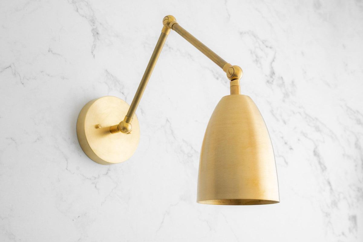 Raw brass adjustable wall sconce with conical shade and swivel arm on white marble wall. - SCONCE MODEL NO. 0107