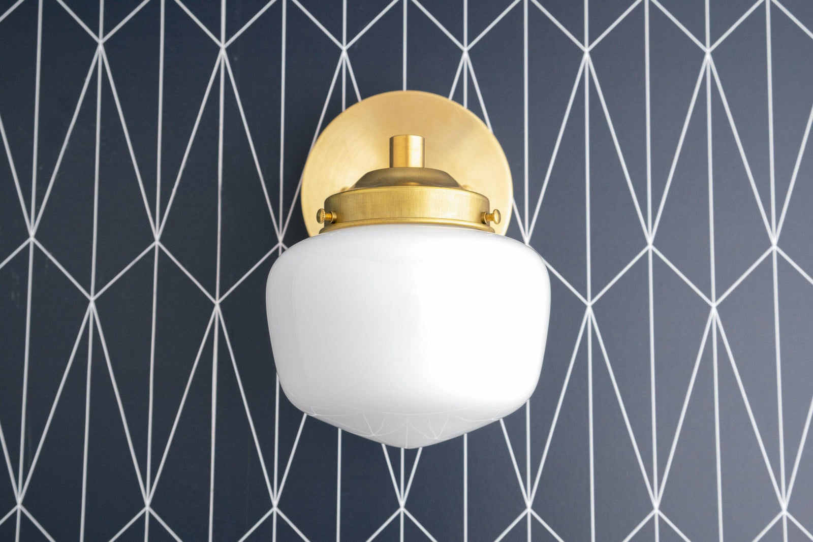 Art Deco wall sconce with round white globe shade and polished brass semi-flush mounting against geometric black and white. - SCONCE MODEL NO. 7321