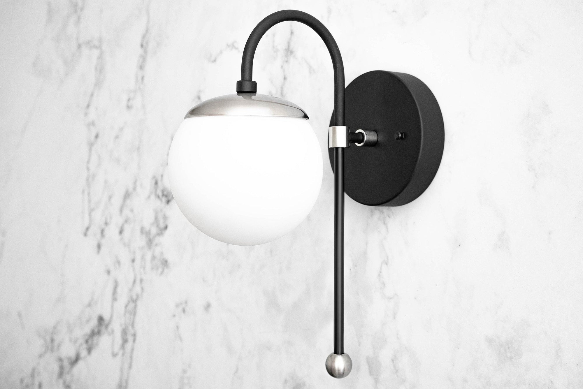 Art Deco semi-flush black sconce with white glass globe and curved arm on marble wall. - SCONCE MODEL NO. 1045