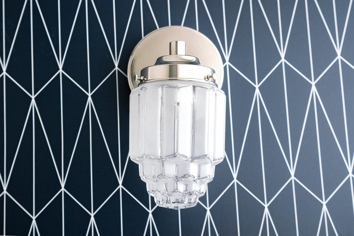 Art Deco polished nickel wall sconce with geometric clear glass globe on black and white patterned wall. - SCONCE MODEL NO. 6130