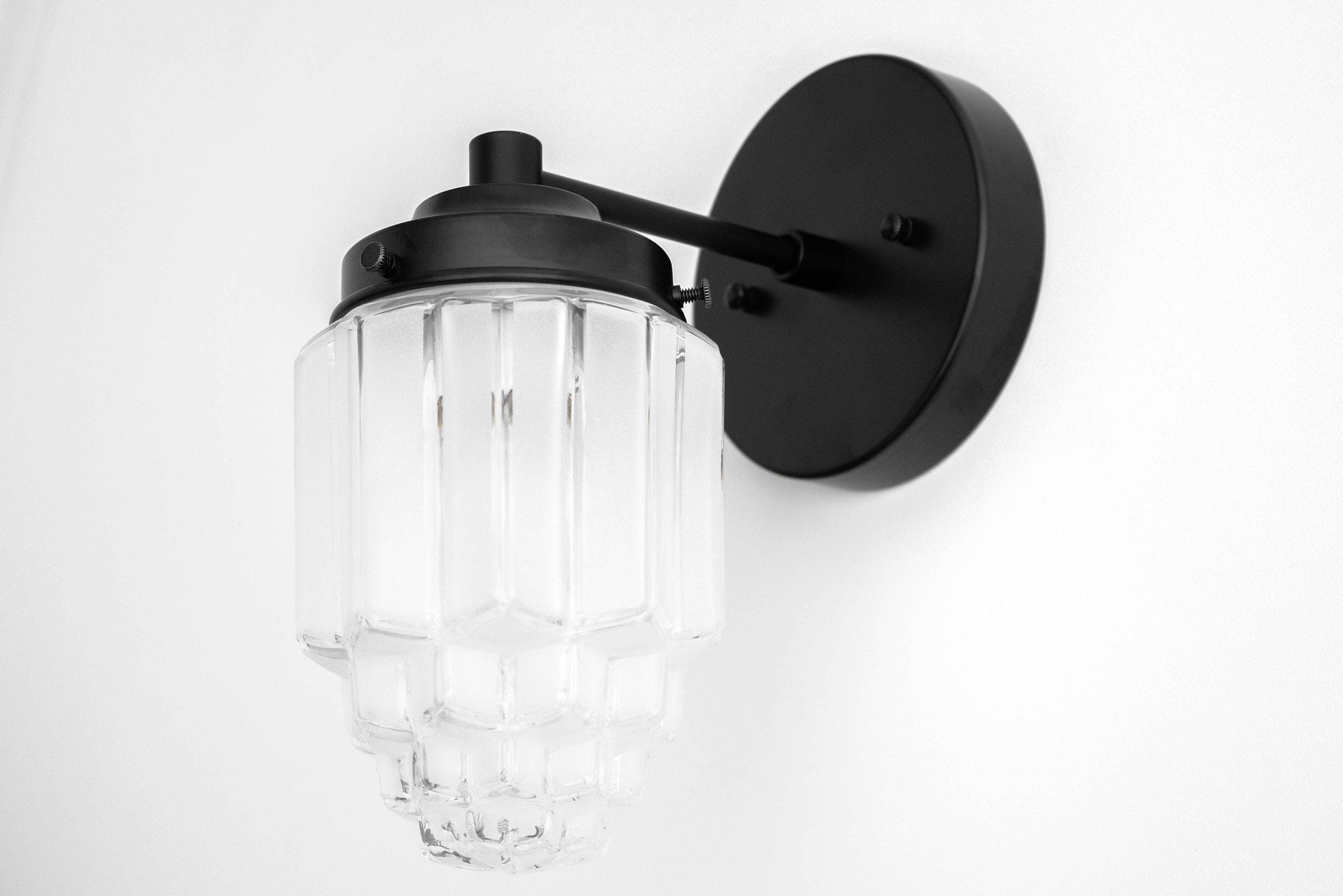 Black metal Art Deco wall sconce with clear tiered glass globe shade and round backplate. - SCONCE MODEL NO. 6130