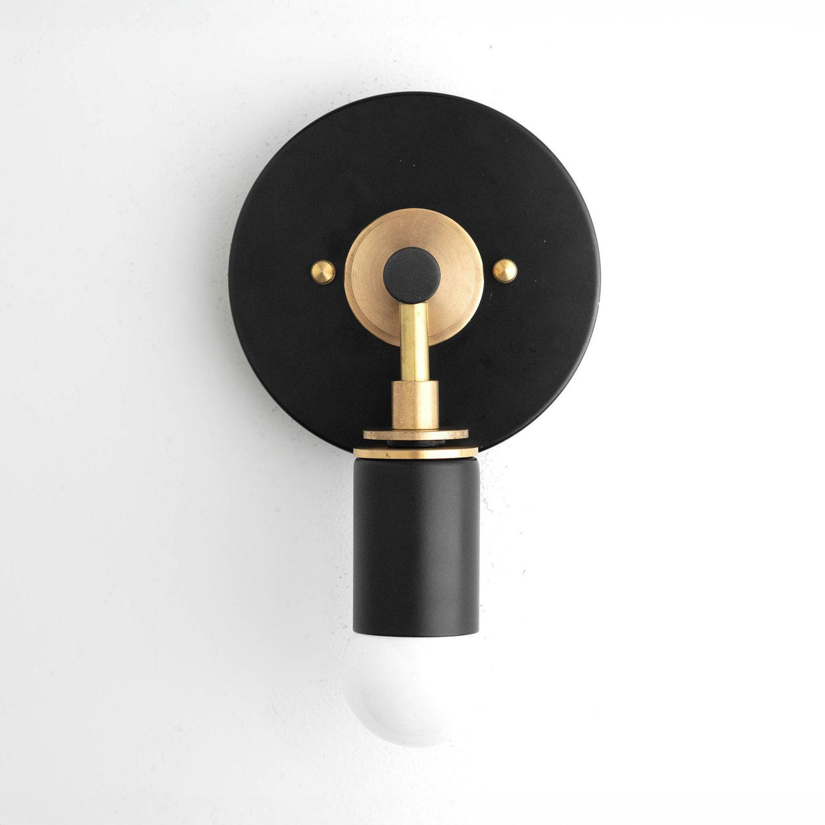 Sconce with a Black round backplate and socket and a Raw or Sealed Brass arm, with a bare bulb. - SCONCE MODEL NO. 1128
