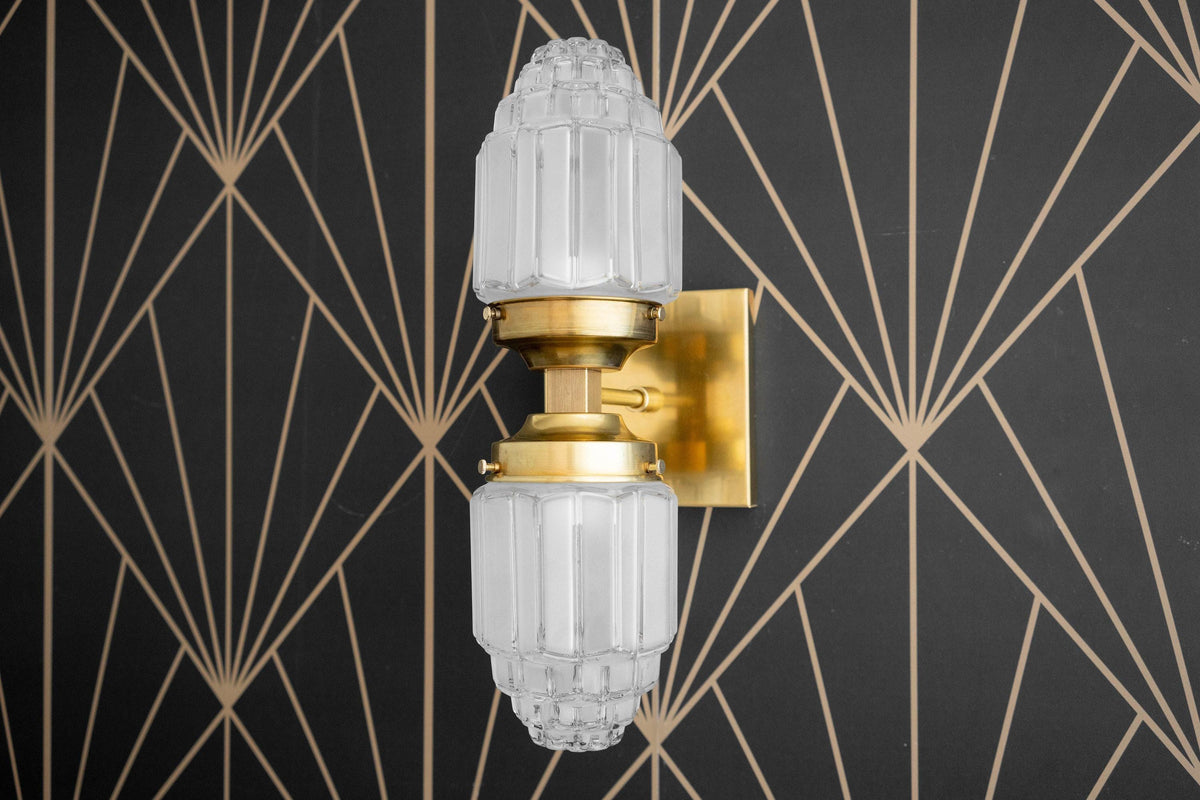 Art Deco raw brass wall sconce with two faceted glass globes and geometric backplate. - SCONCE MODEL NO. 7180