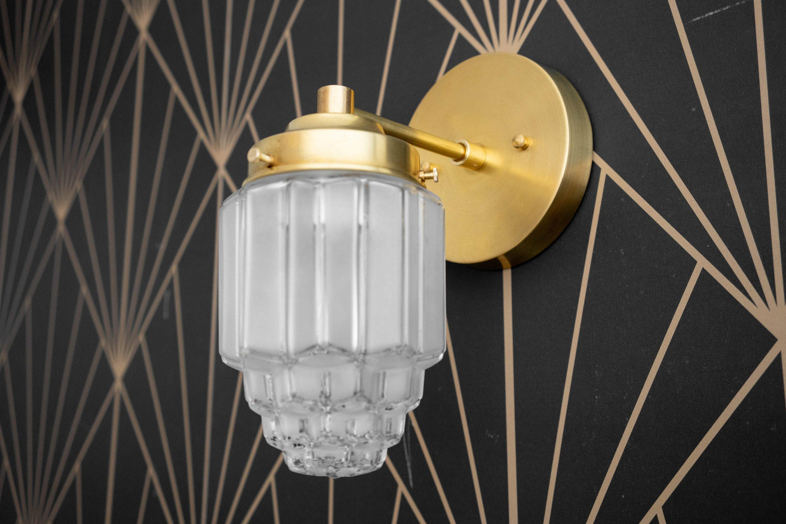 Art Deco brass wall sconce with ribbed frosted glass globe and decorative bottom detail. - SCONCE MODEL NO. 6130