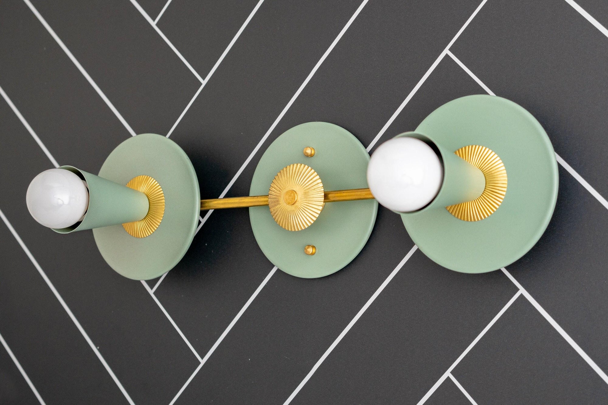 Art Deco raw brass vanity light with two exposed bulbs and green circular backplates on dark tile wall. - VANITY LIGHT MODEL NO. 4473