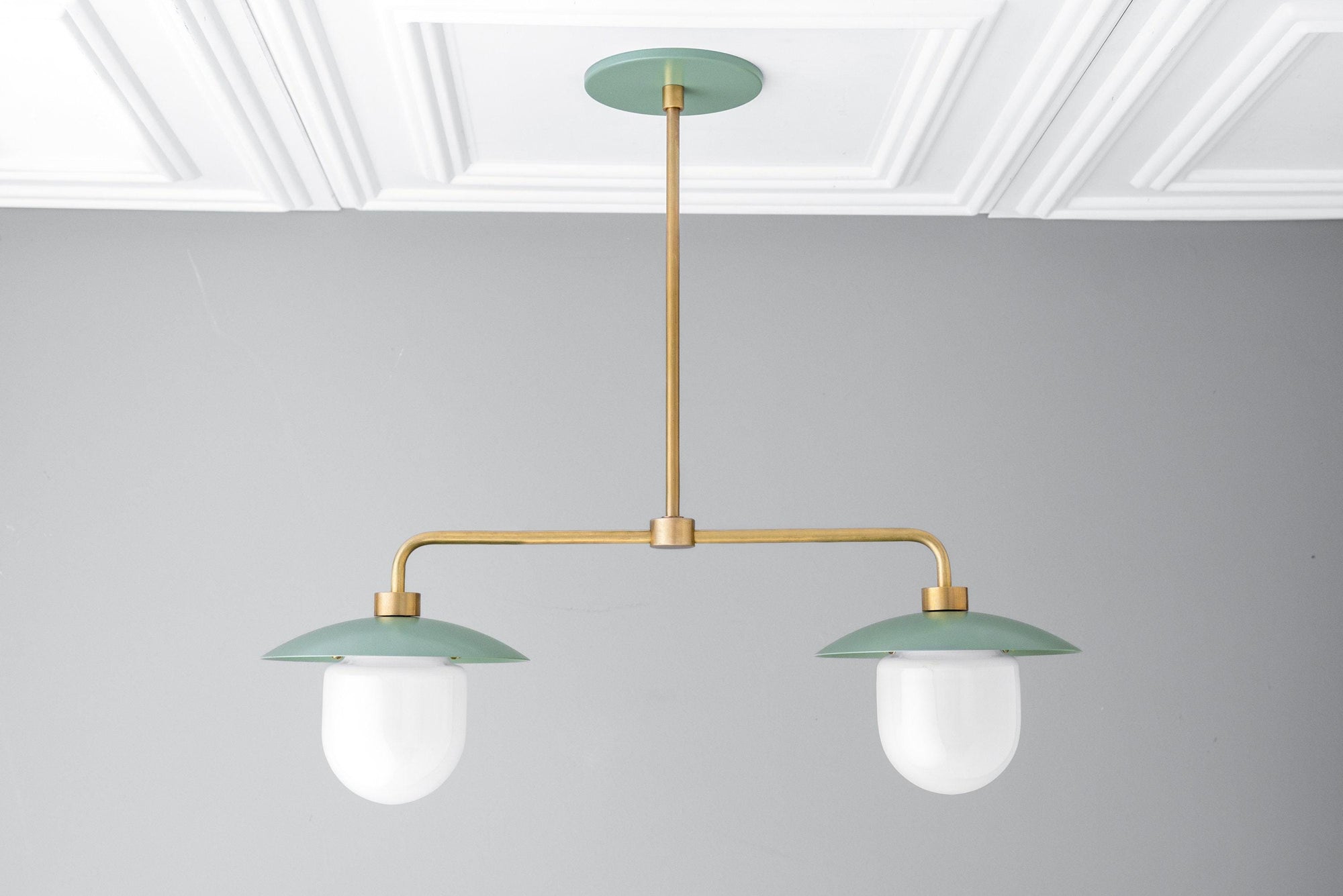 Mid-century modern chandelier with two green metal shades and brass arms, suspended from ceiling mount. - CHANDELIER MODEL NO. 1727