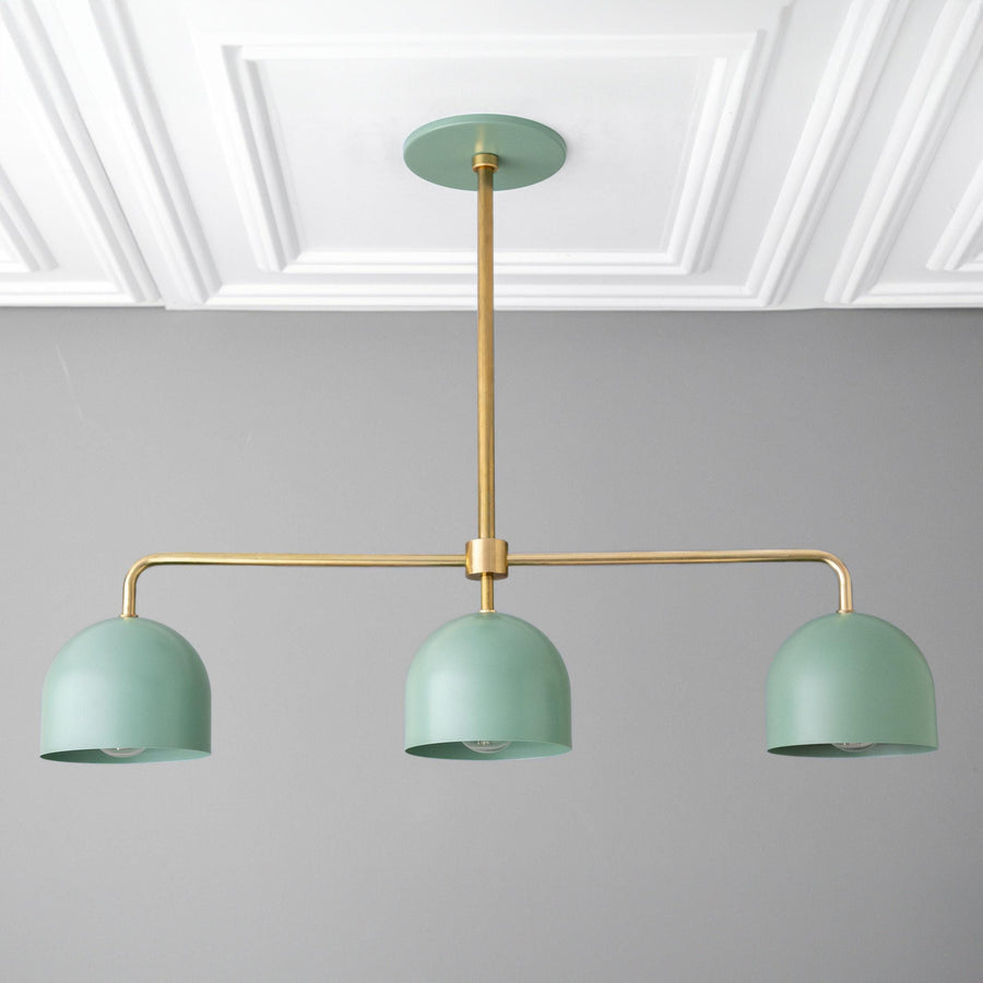 Industrial-style chandelier with three matte green dome shades and brass frame, mounted on a ceiling with white molding. - CHANDELIER MODEL NO. 0285
