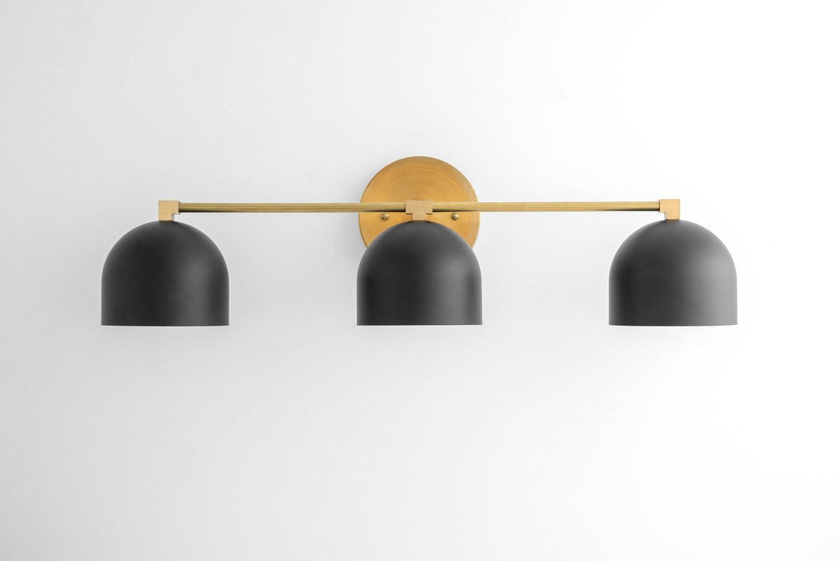 Mid-century modern vanity light with three black dome shades and a brass horizontal bar mount. - VANITY LIGHT MODEL NO. 7565