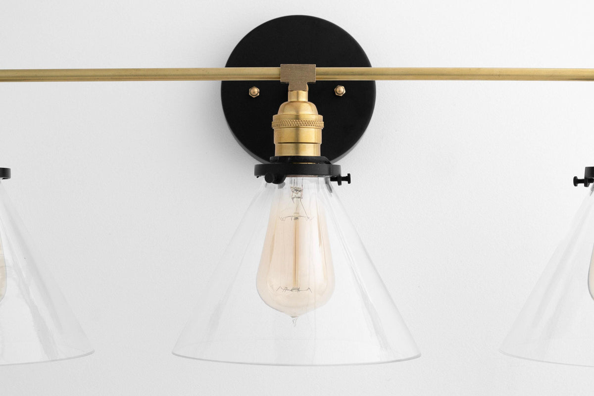 Mid-century modern vanity light with raw brass rod and black round wall mount, clear cone glass shade, and vintage-style. - VANITY LIGHT MODEL NO. 5219