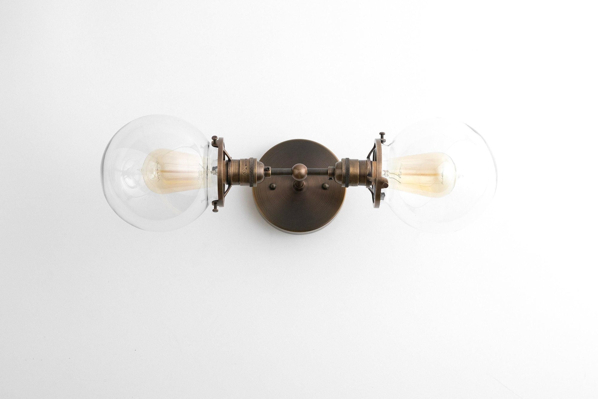 Art Deco style black metal vanity light with two clear globe bulbs and a round wall mount. - VANITY LIGHT MODEL NO. 7350