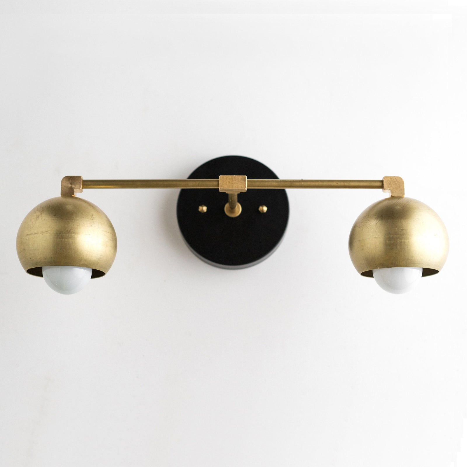 Mid-century modern vanity light with two raw brass dome shades and black circular wall mount. - VANITY LIGHT MODEL NO. 5469