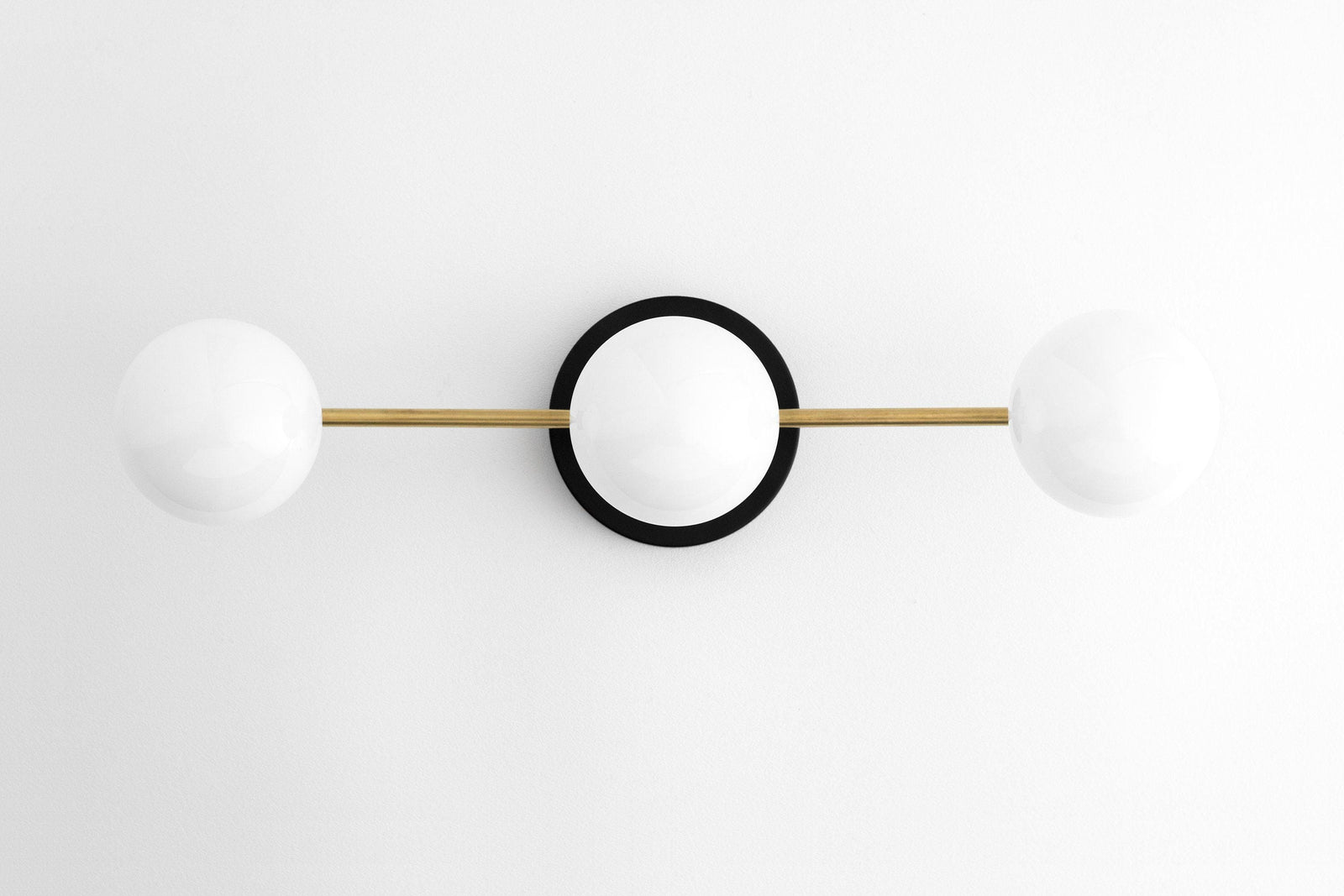 Mid-century modern vanity light with two white glass globes and raw brass rod on black circular base. - VANITY LIGHT MODEL NO. 0518