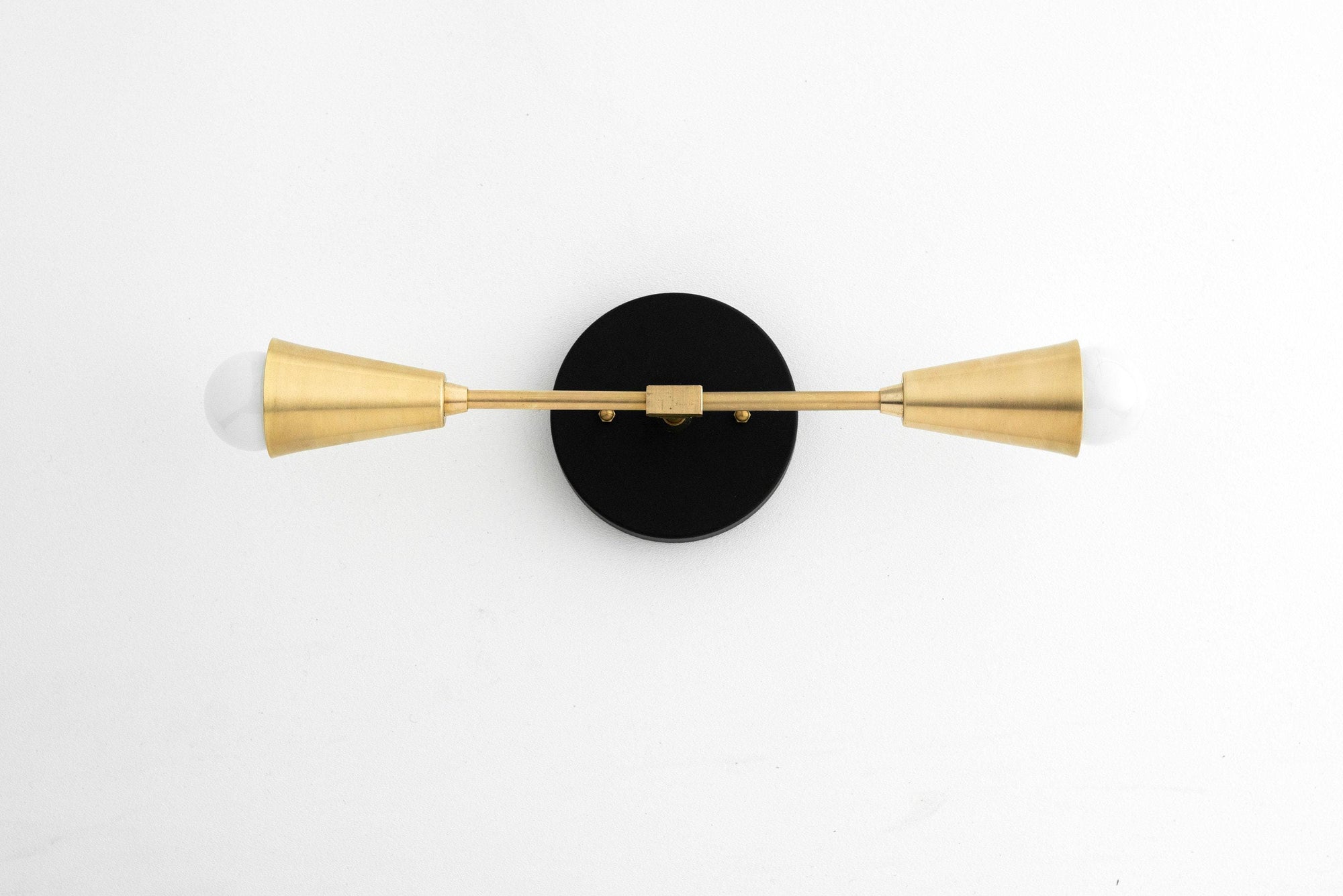 Mid-century modern two-bulb vanity light with raw brass conical shades and black circular backplate. - VANITY LIGHT MODEL NO. 3209