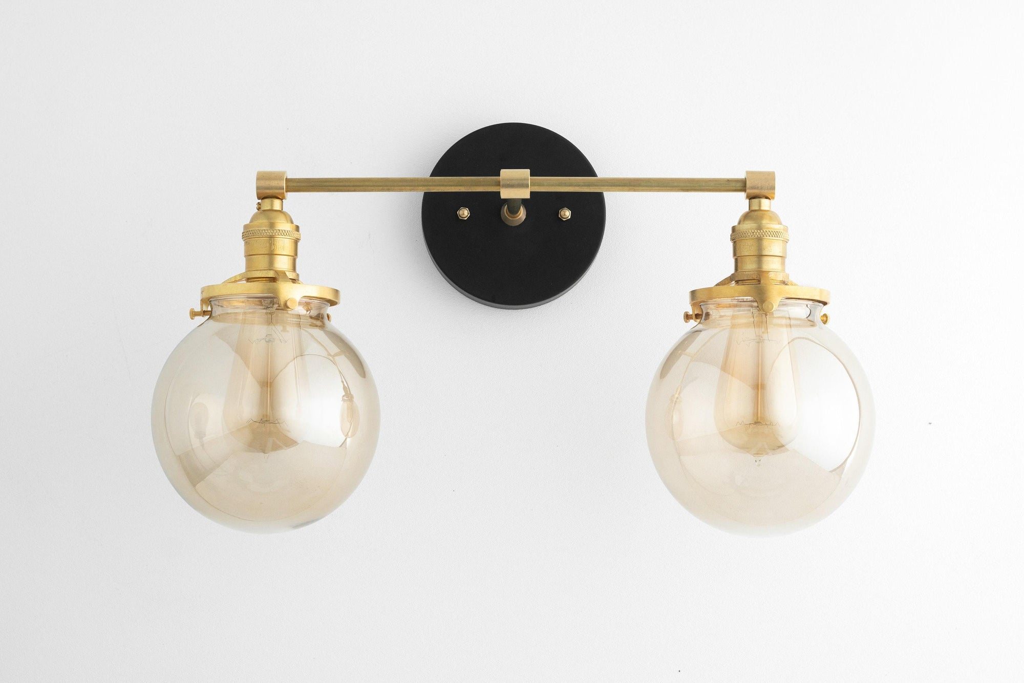 Mid-century modern 2-bulb vanity light with raw brass finish and clear globe shades on black circular mount. - VANITY LIGHT MODEL NO. 4270
