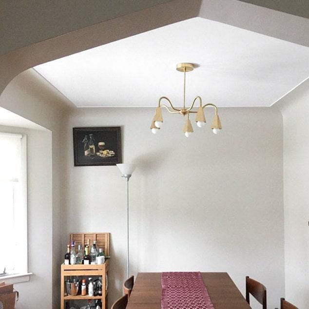 Mid-century modern raw brass chandelier with six exposed bulbs, hanging above wooden dining table with red runner. - CHANDELIER MODEL NO. 2464