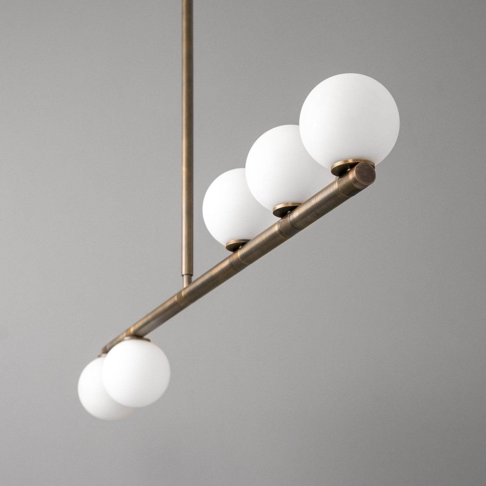 Linear chandelier with five frosted white globe lights on antique brass frame and rod. - CHANDELIER MODEL NO. 6507