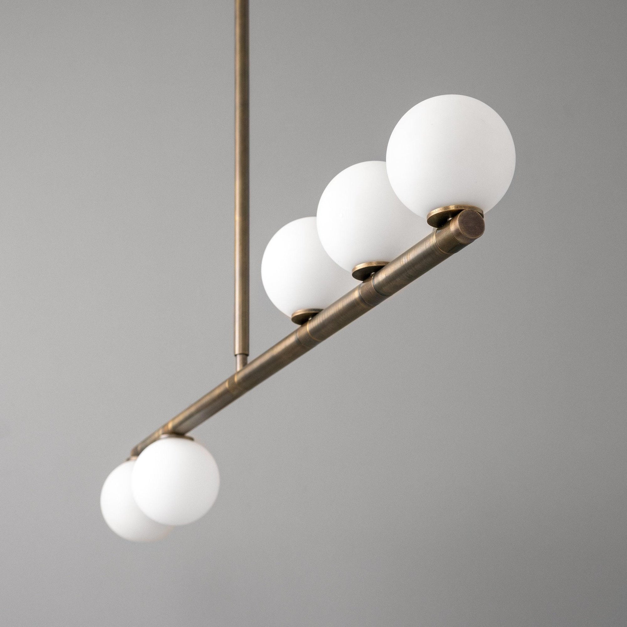 Linear chandelier with five frosted white globe lights on antique brass frame and rod. - CHANDELIER MODEL NO. 6507
