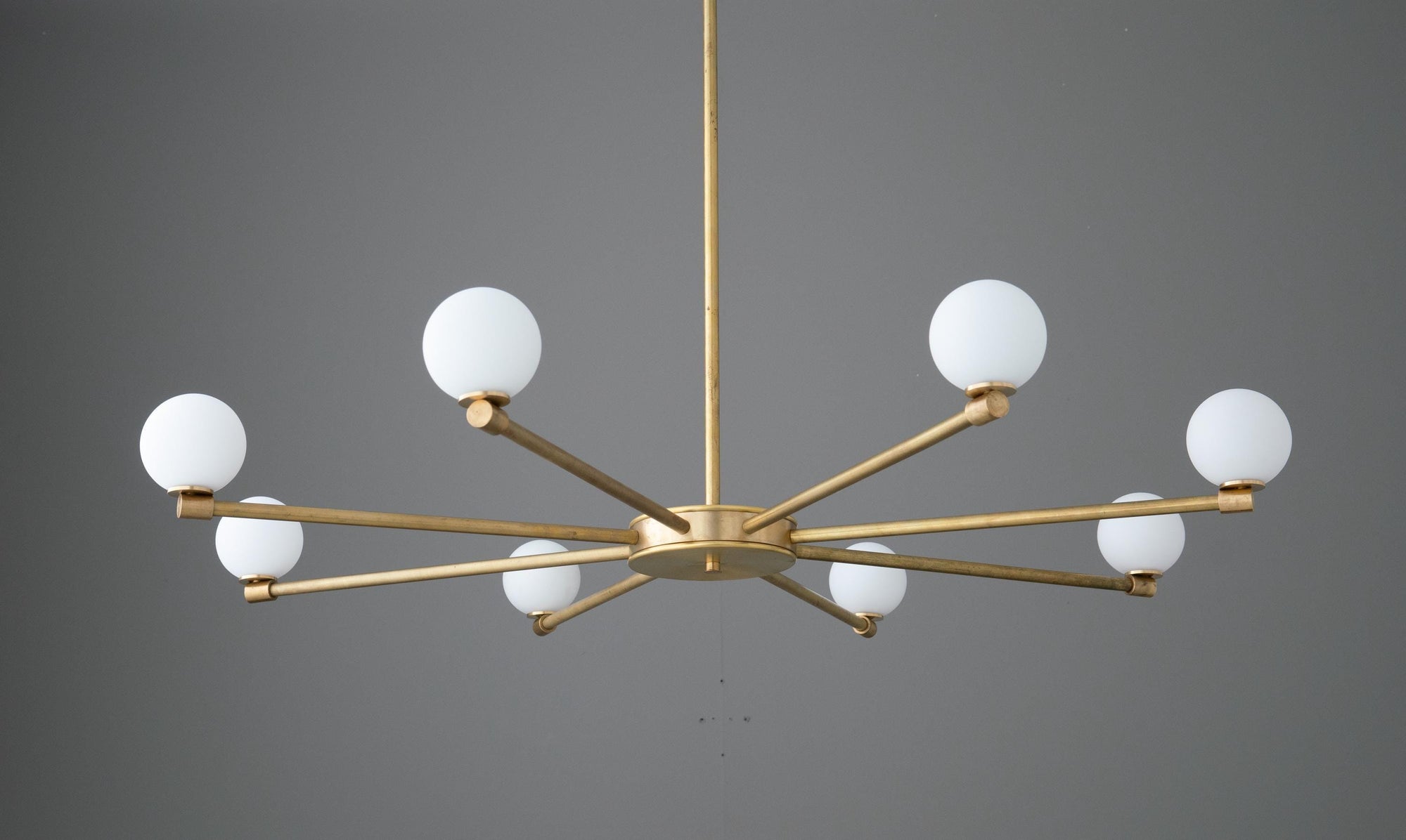 Raw brass chandelier with eight white globe lights in a minimalist starburst design. - CHANDELIER MODEL NO. 3192