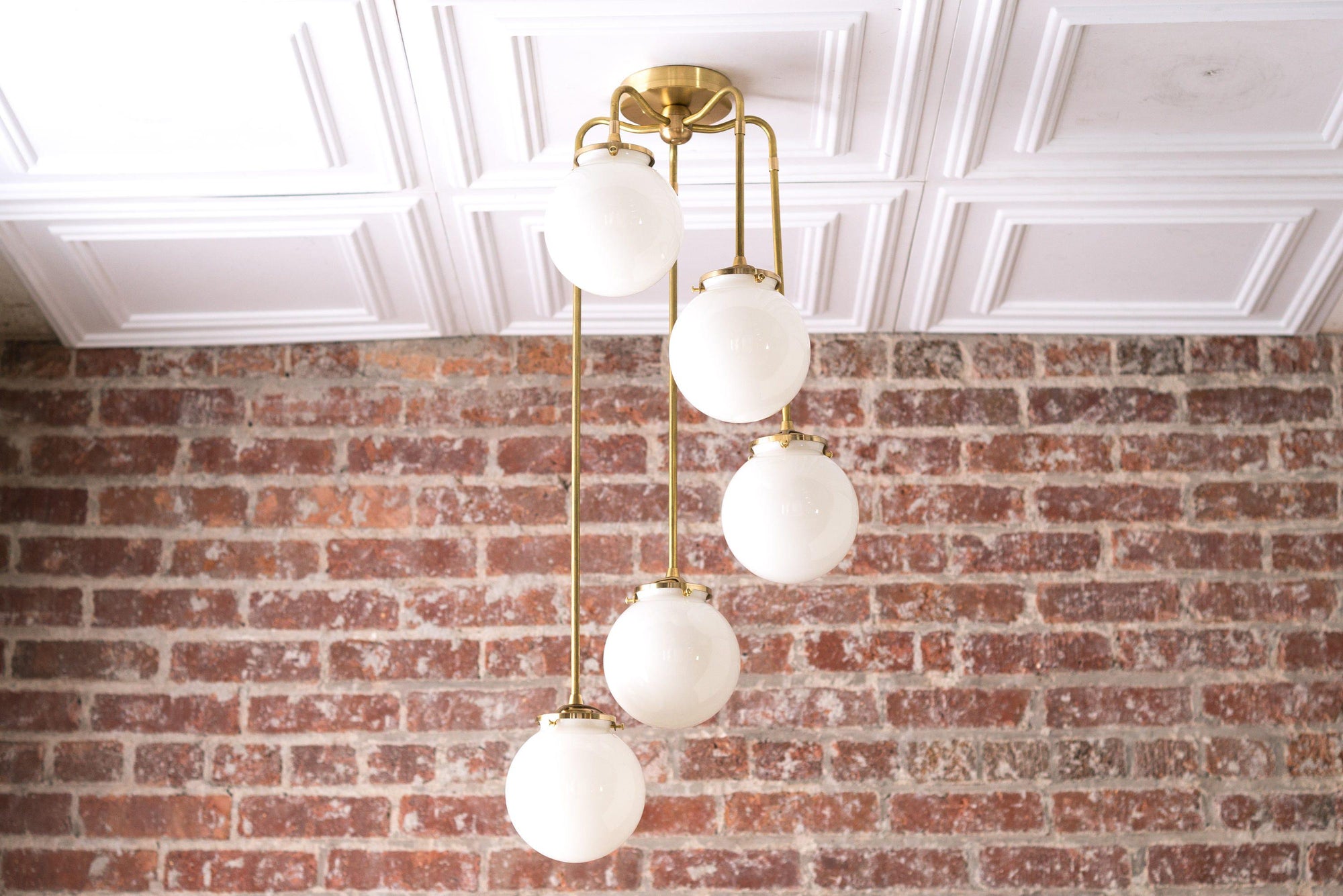 Mid-century modern raw brass chandelier with six white globe lights hanging in staggered arrangement. - CHANDELIER MODEL NO. 1809
