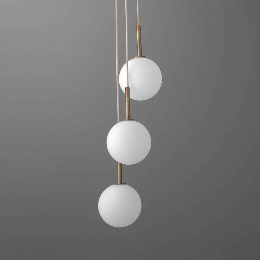 Three-tier chandelier with frosted white glass globes and brushed brass accents hanging on tan cords against gray background. - CHANDELIER MODEL NO. 4701