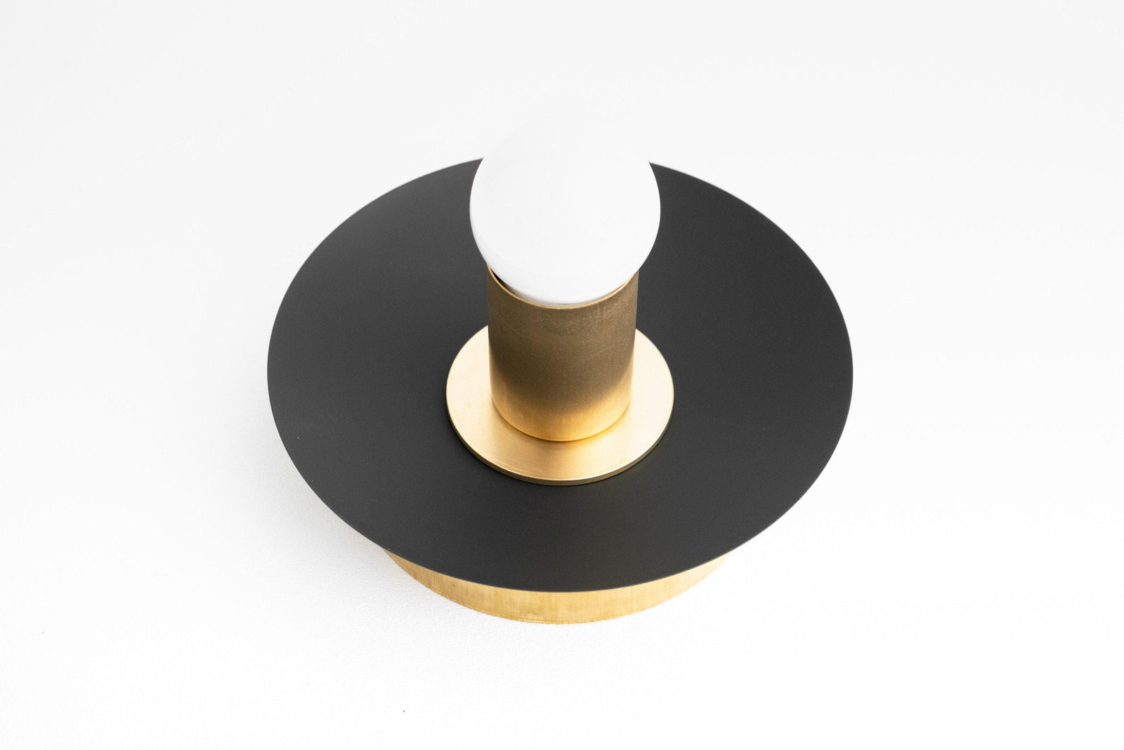 Art Deco black and brass flush mount sconce with bare bulb and circular backplate. - SCONCE MODEL NO. 7004