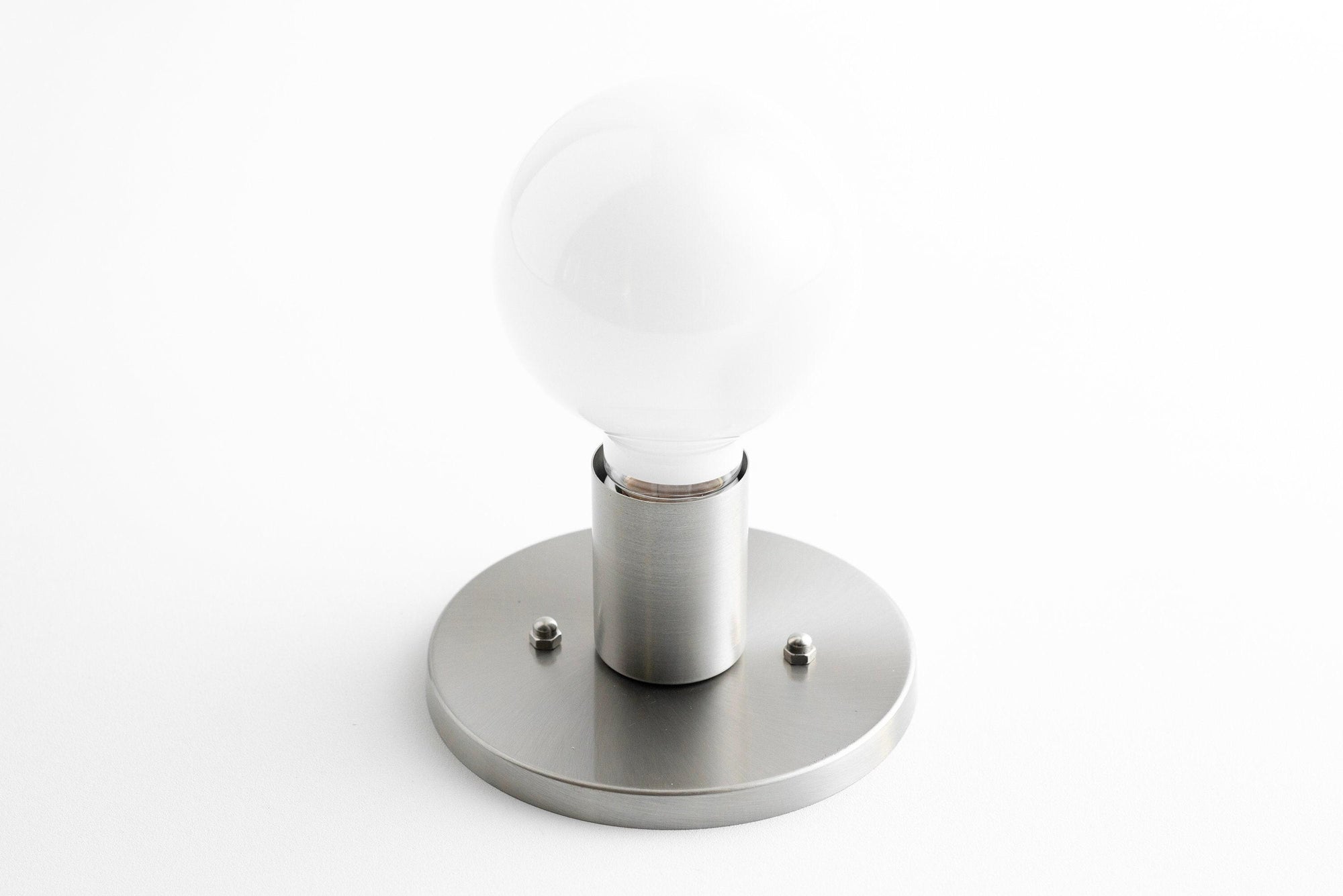 Mid-century modern brushed nickel flush sconce with exposed bulb and round base. - SCONCE MODEL NO. 2057