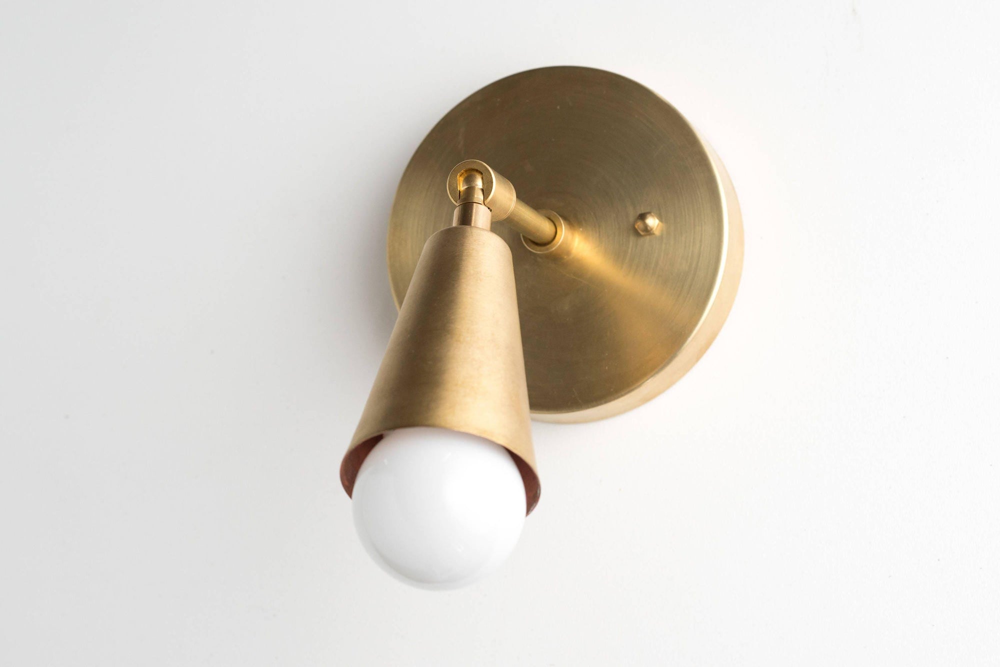 Mid-century modern raw brass wall sconce with adjustable cone-shaped shade and exposed bulb. - SCONCE MODEL NO. 4339