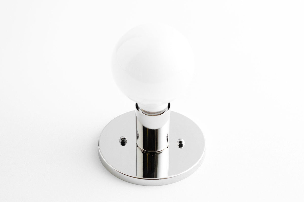 Mid-century modern polished nickel wall sconce with exposed round white bulb and flush mount base. - SCONCE MODEL NO. 2057