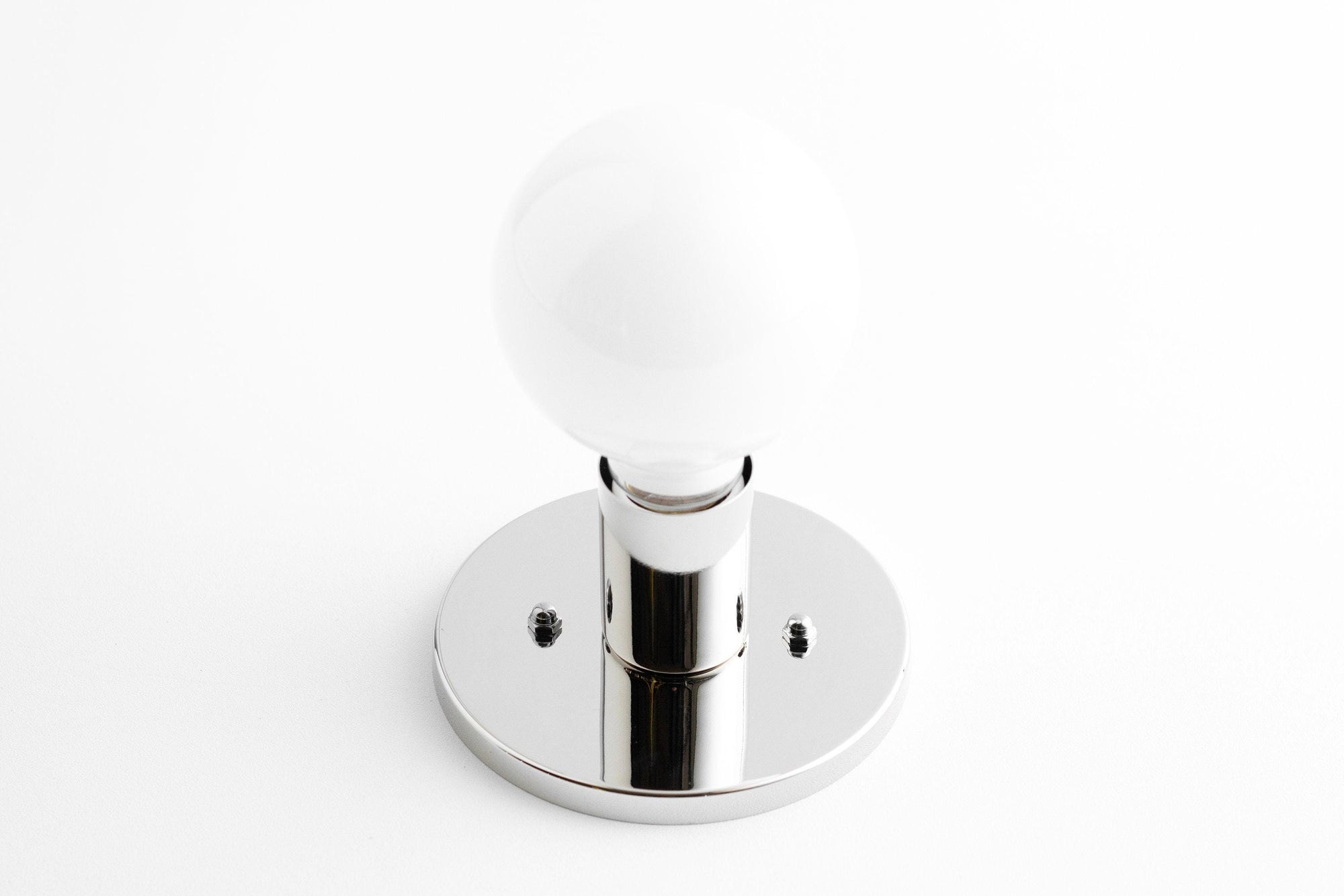 Mid-century modern polished nickel wall sconce with exposed round white bulb and flush mount base. - SCONCE MODEL NO. 2057