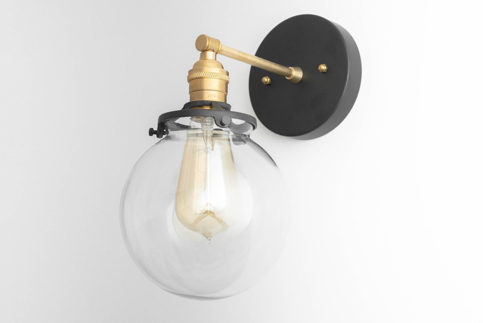 Mid-century modern wall sconce with clear globe and raw brass fixture on matte black mount. - SCONCE MODEL NO. 5456