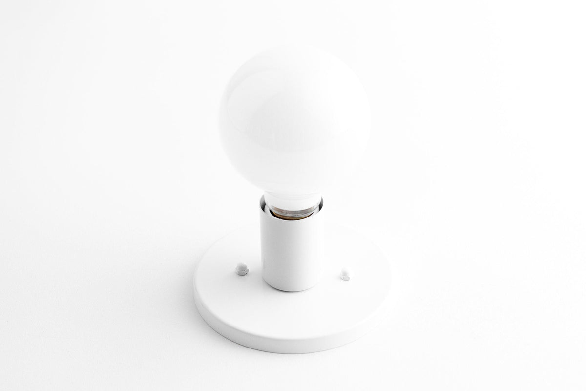 Mid-century modern white flush sconce with round frosted glass bulb and brass accents. - SCONCE MODEL NO. 2057