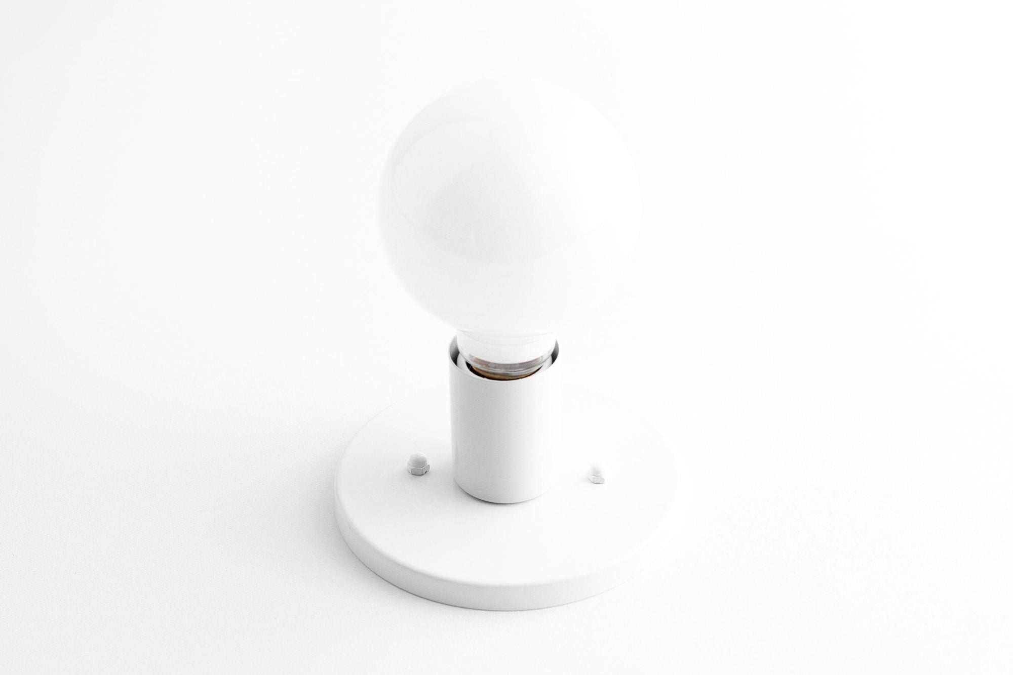 Mid-century modern white flush sconce with round frosted glass bulb and brass accents. - SCONCE MODEL NO. 2057
