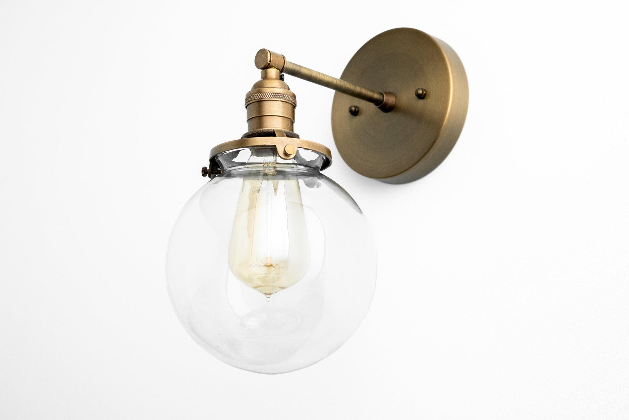 Mid-century modern wall sconce with clear glass globe and raw brass finish mount. - SCONCE MODEL NO. 5456