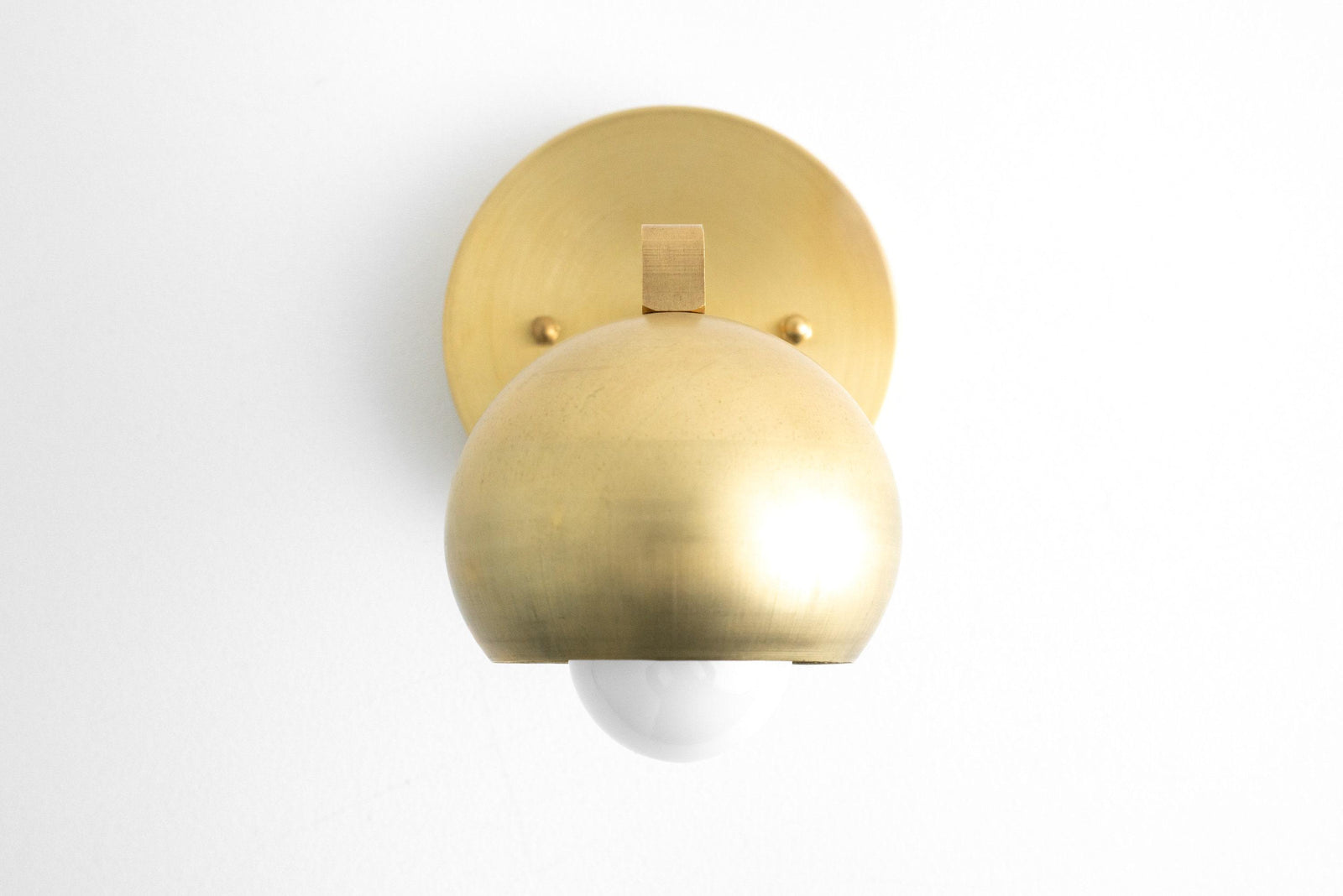 Mid-century brass wall sconce with rounded shade and white bulb. - SCONCE MODEL NO. 0053